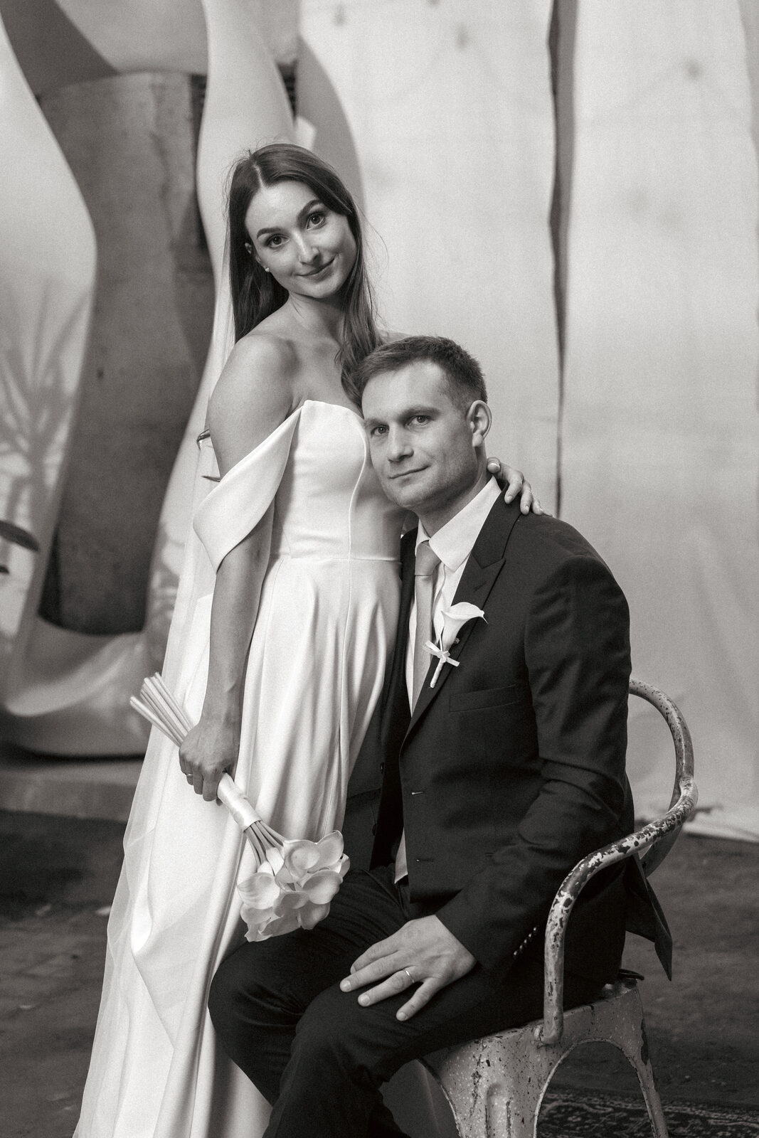 Bride and groom seated together on an old chair