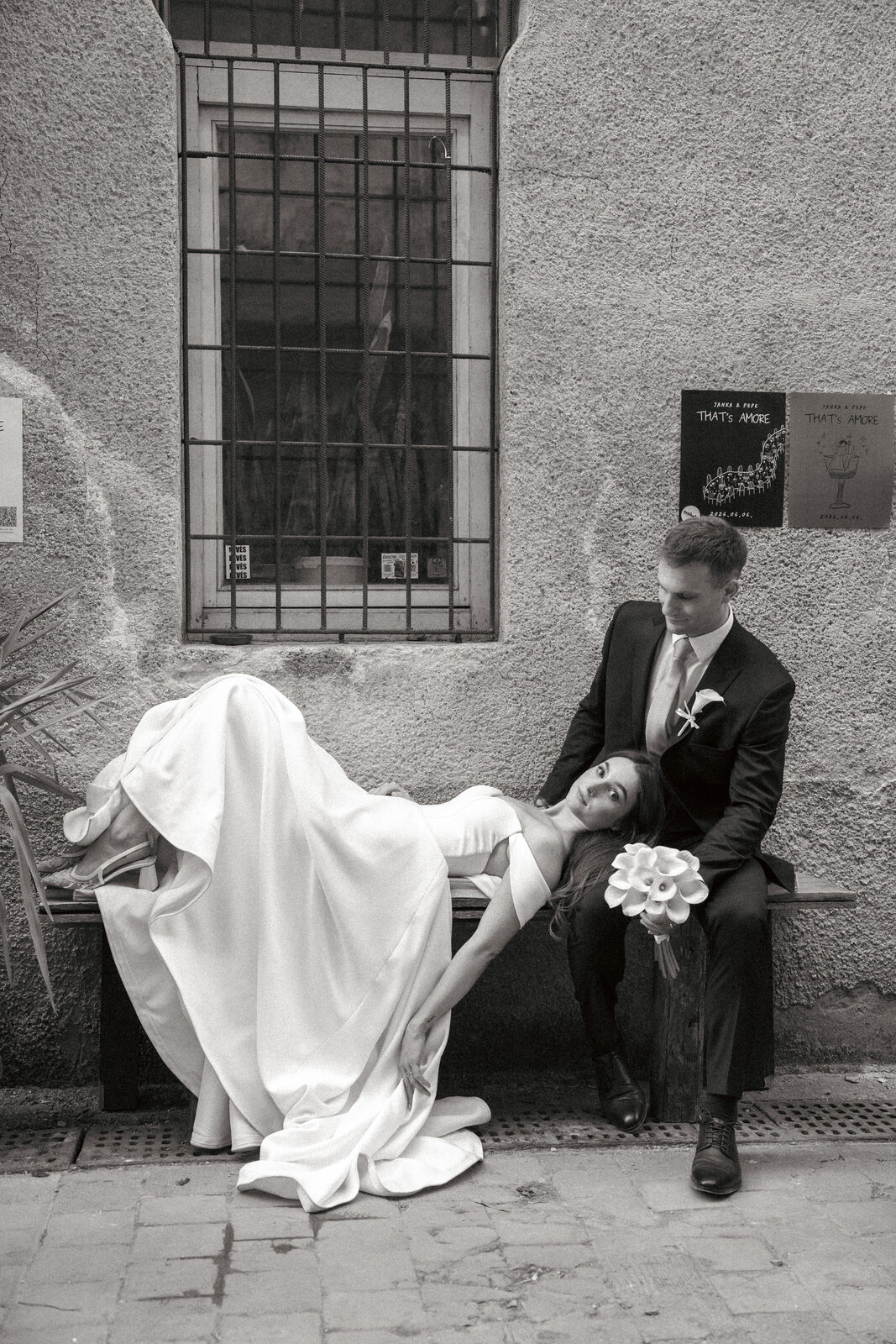 Bride leaning back on a bench while the groom holds her