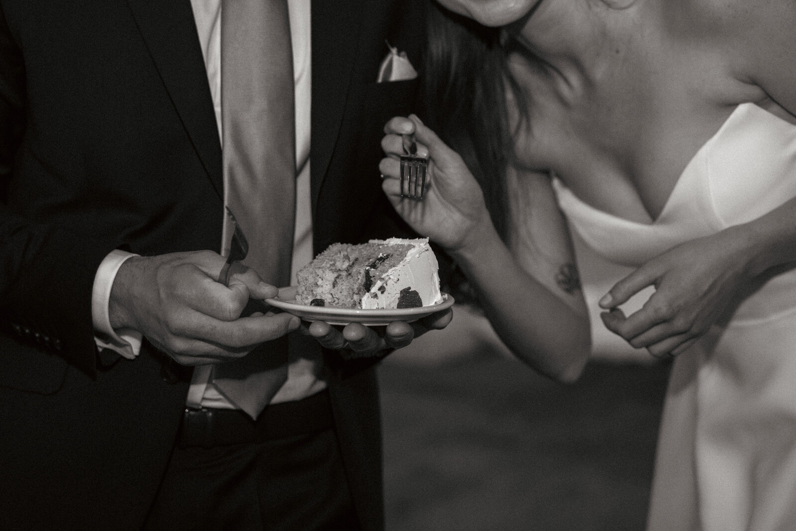 Hands sharing a slice of wedding cake