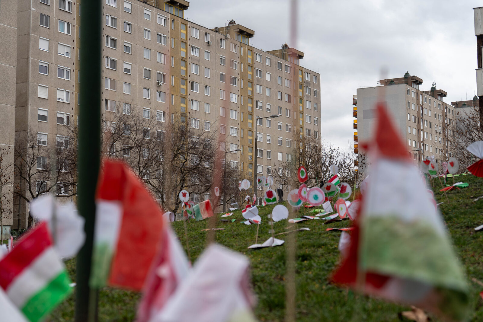 Paper flags and decorations on a grassy hillside between apartment blocks